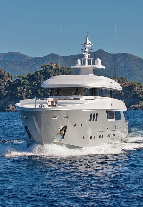 Motor yacht at anchor before a mountain coastline